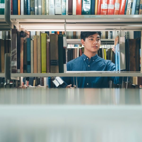 asian-man-university-student-choosing-and-picking-off-book-from-bookshelf-in-college-library-for_t20_Jomo7O
